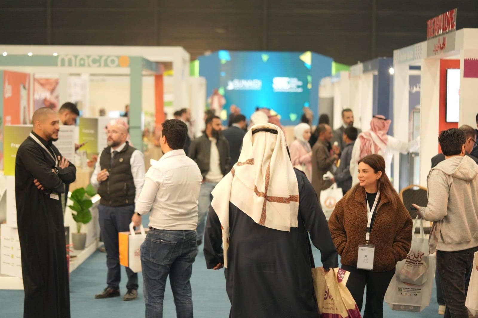 Visitors filling the main aisle of the exhibition hall between brand stands